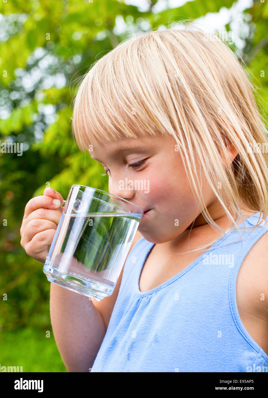 Cute little girl drinking water outdoors Banque D'Images