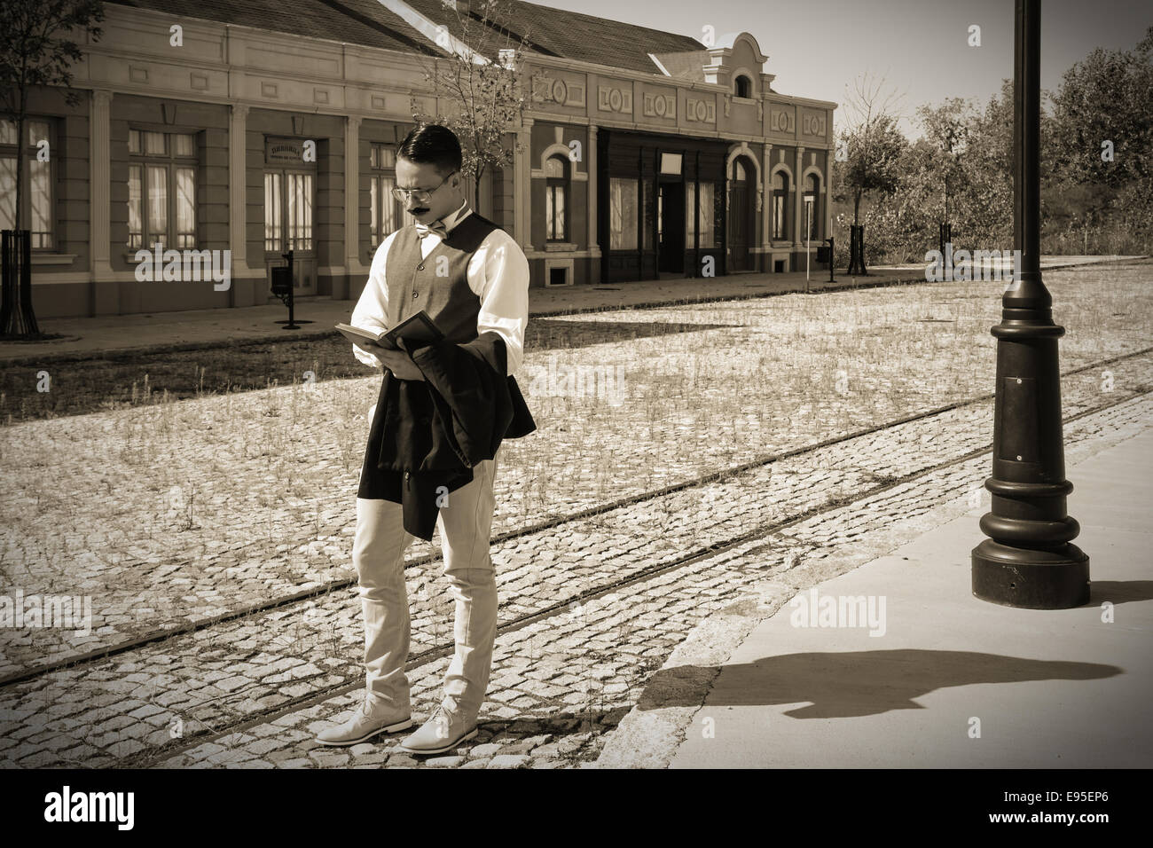 L'homme en costume avec des lunettes et moustaches lecture livre dans la vieille ville de retro, effet noir et blanc dans l'image Banque D'Images