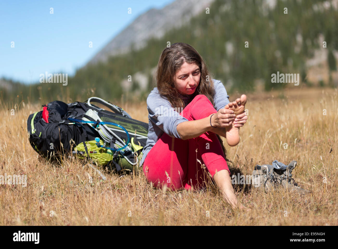 Woman rubbing her pieds sur un sac à dos voyage en Oregon's Montagnes Wallowa. Banque D'Images