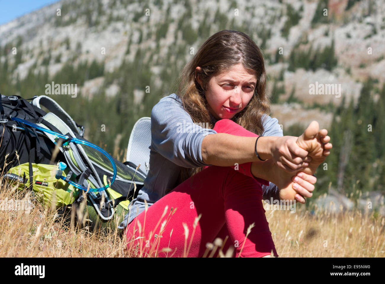 Woman rubbing her pieds sur un sac à dos voyage en Oregon's Montagnes Wallowa. Banque D'Images