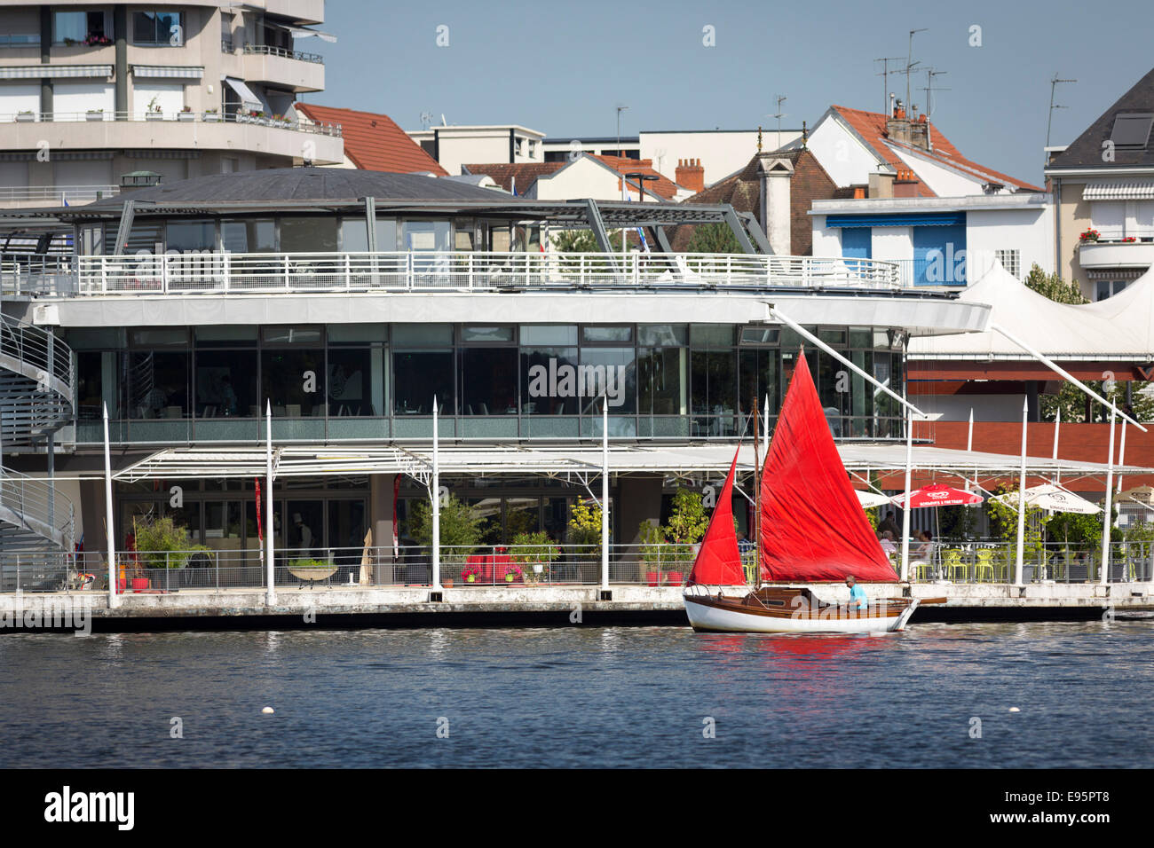 En été, un petit bateau à voile rouge sur le lac de l'Allier (Vichy). Petit voilier à voiles rouges sur le Lac d'Allier, à Vichy. Banque D'Images