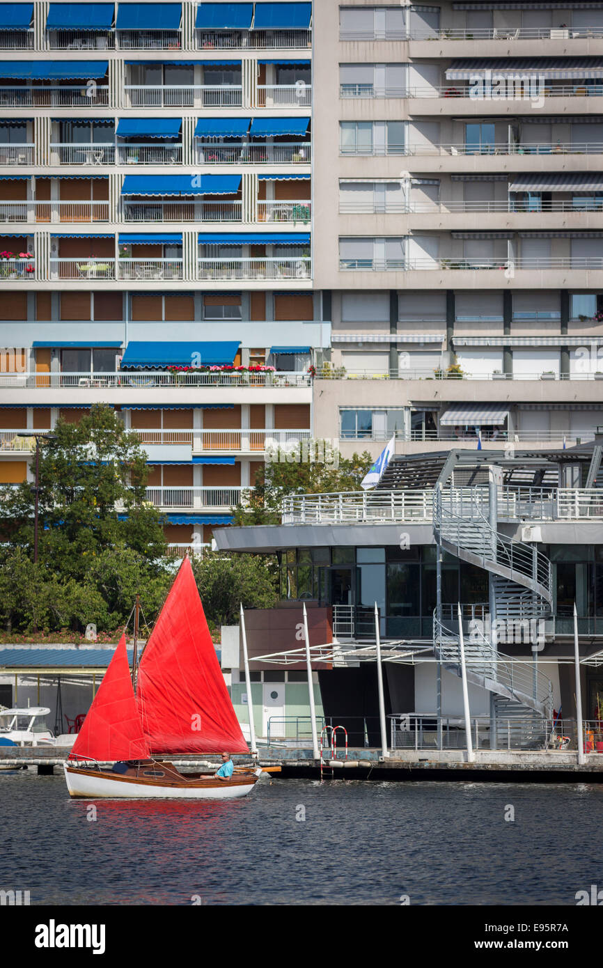 En été, un petit bateau à voile rouge sur le lac de l'Allier (Vichy). Petit voilier à voiles rouges sur le Lac d'Allier, à Vichy. Banque D'Images