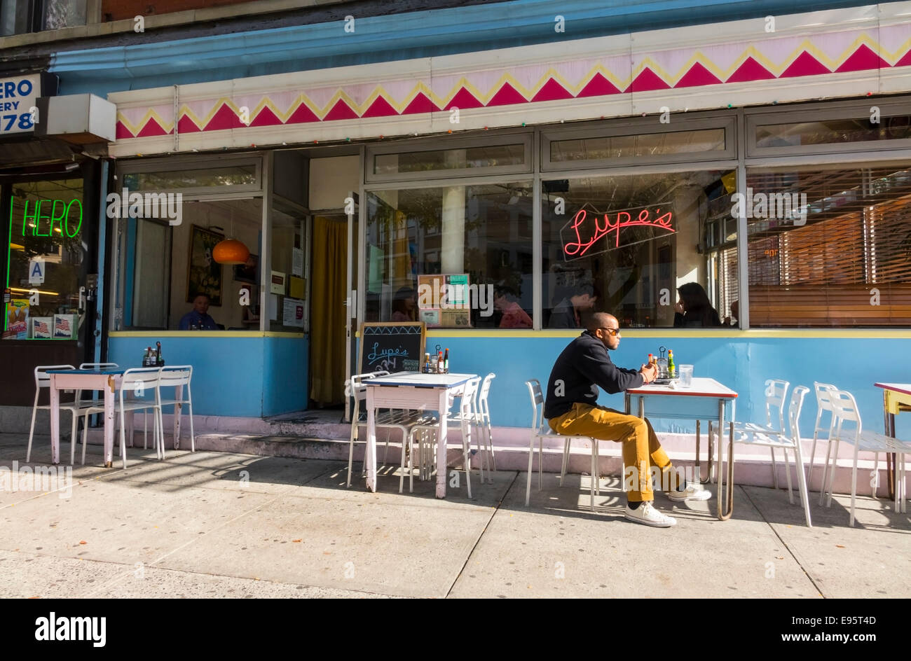 Un homme noir assis à une table d'extérieur seul en attente de sa commande de nourriture mexicaine dans Soho à New York City Banque D'Images