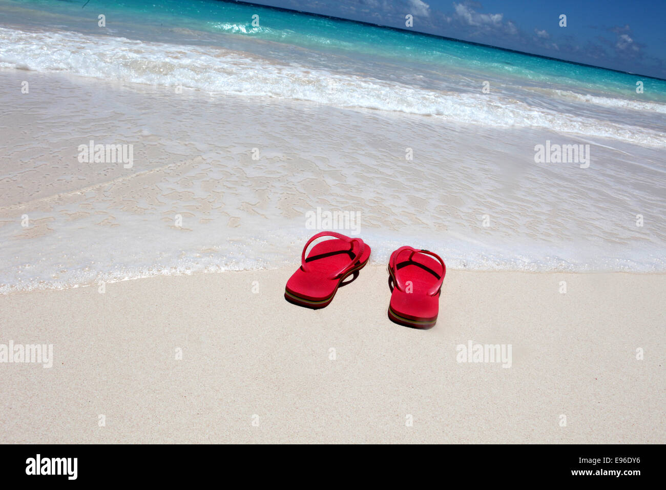 Flip flop rouge sur la plage contre l'eau claire Banque D'Images