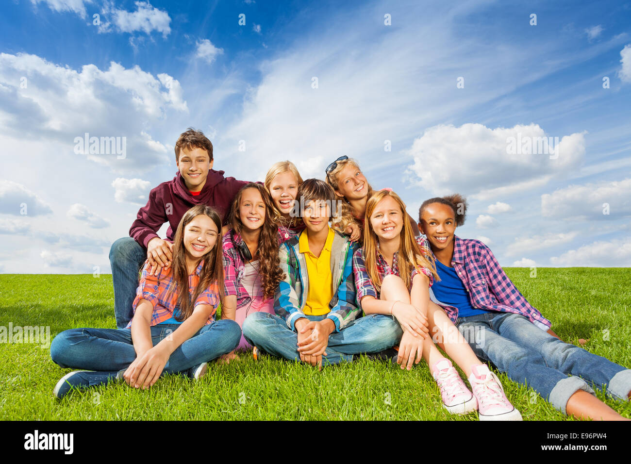 Happy international kids s'asseoir près de l'herbe Banque D'Images