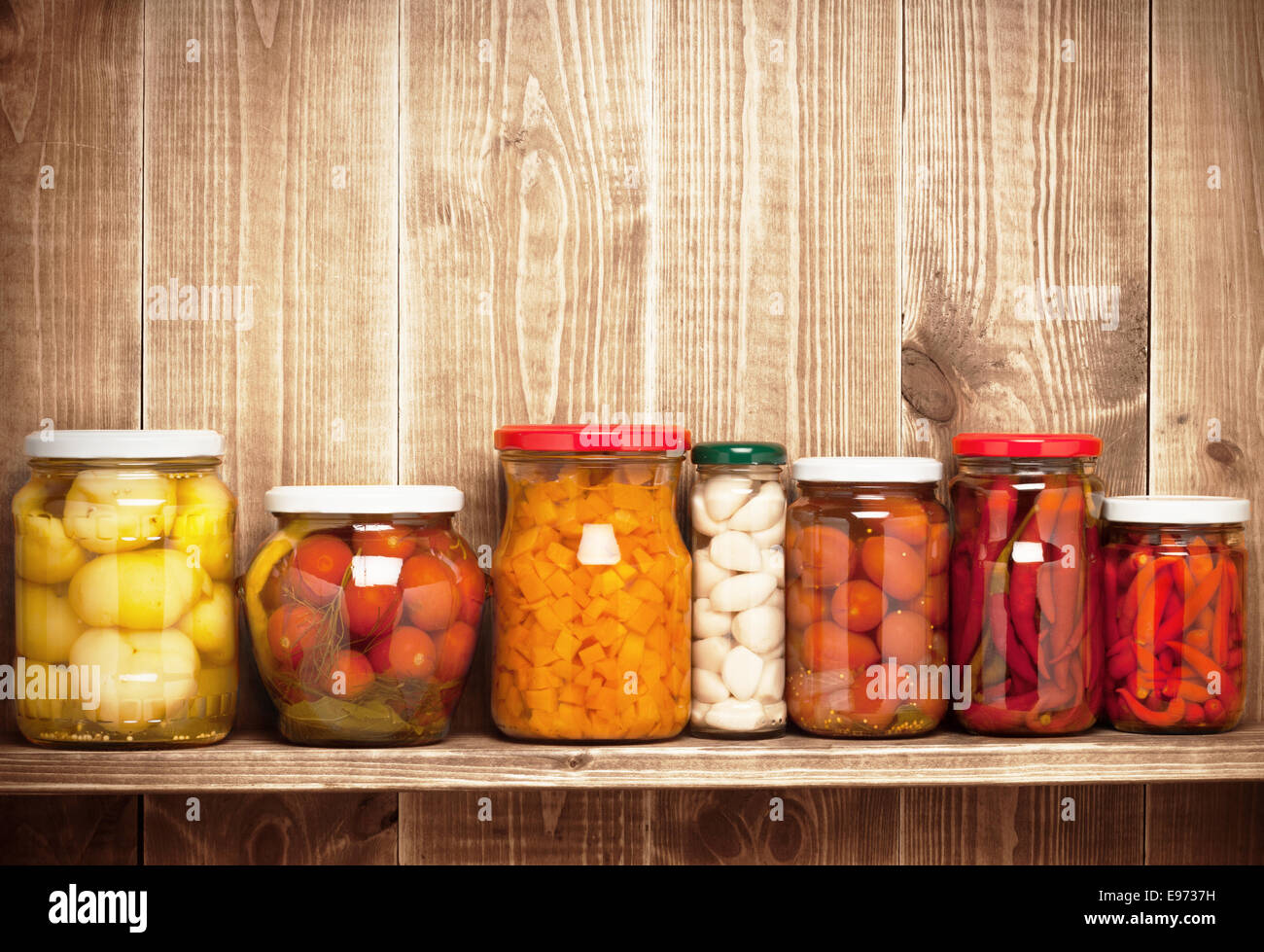 Conserves de légumes d'automne sur une étagère près d'un mur en bois Banque D'Images