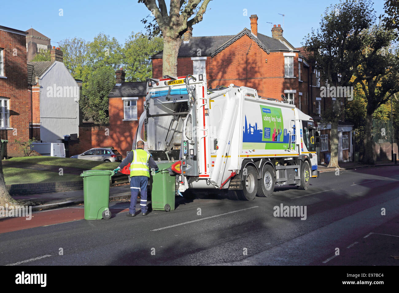 Un entrepreneur se jette une branche de refuser wheely bin dans un véhicule de collecte de déchets modernes Banque D'Images
