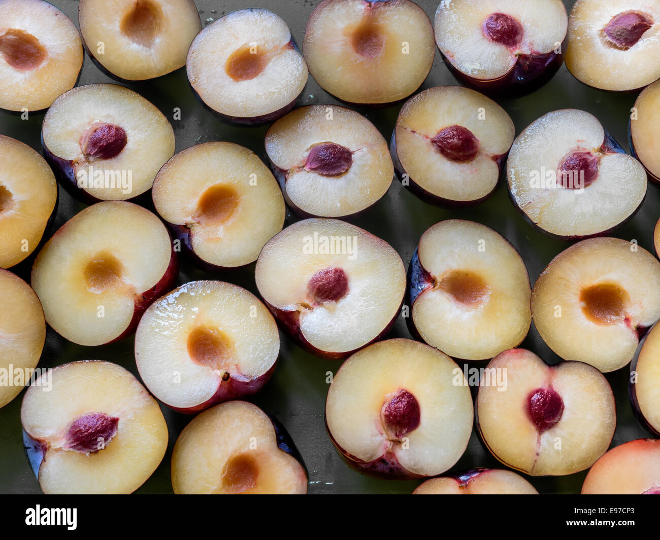 Les prunes violettes, coupées en deux avec des pierres Banque D'Images