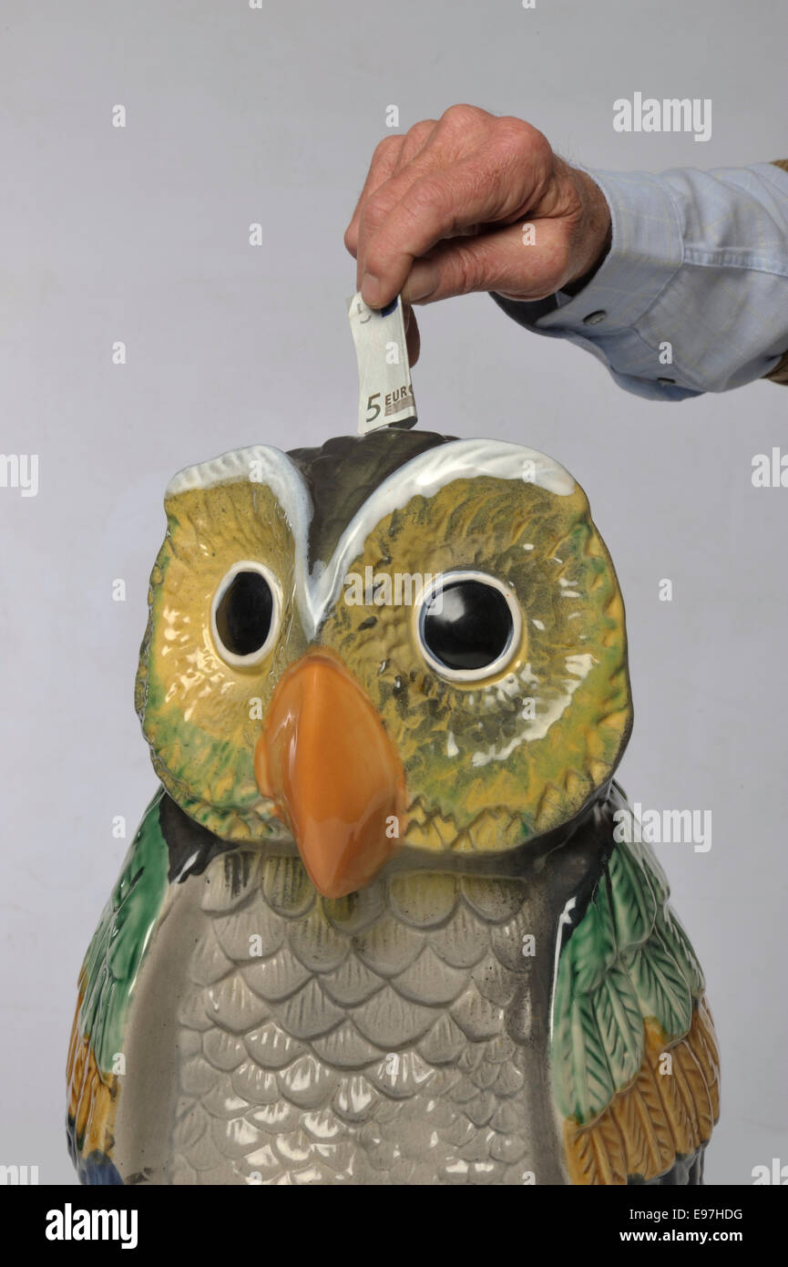 Mettre de l'argent dans la boîte de l'argent en forme de hibou Banque D'Images