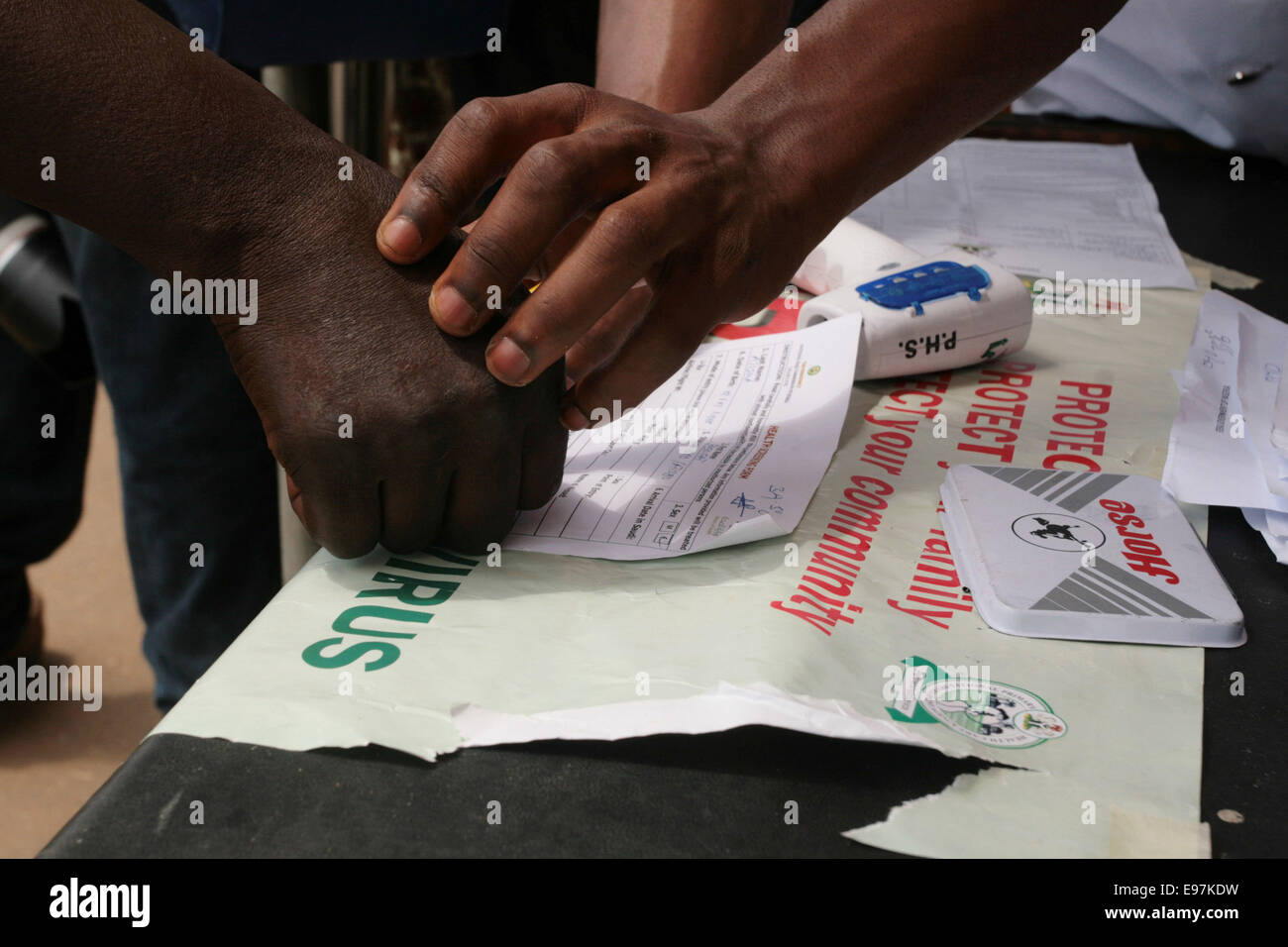 Agent de santé contribue à un analphabète de pouce imprimer un document dans le cadre de l'examen préalable pour les symptômes du virus Ebola à Lagos Nigeria Banque D'Images