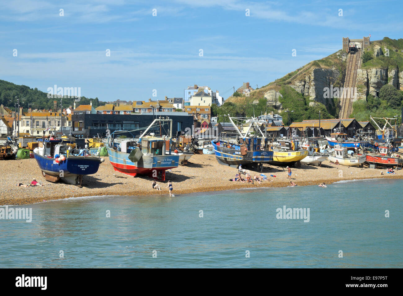 Les gens nagent et se bronzer sur la plage de Hastings stade, devant les chalutiers et la Hastings Contemporary Art Gallery, East Sussex, Royaume-Uni, GB Banque D'Images