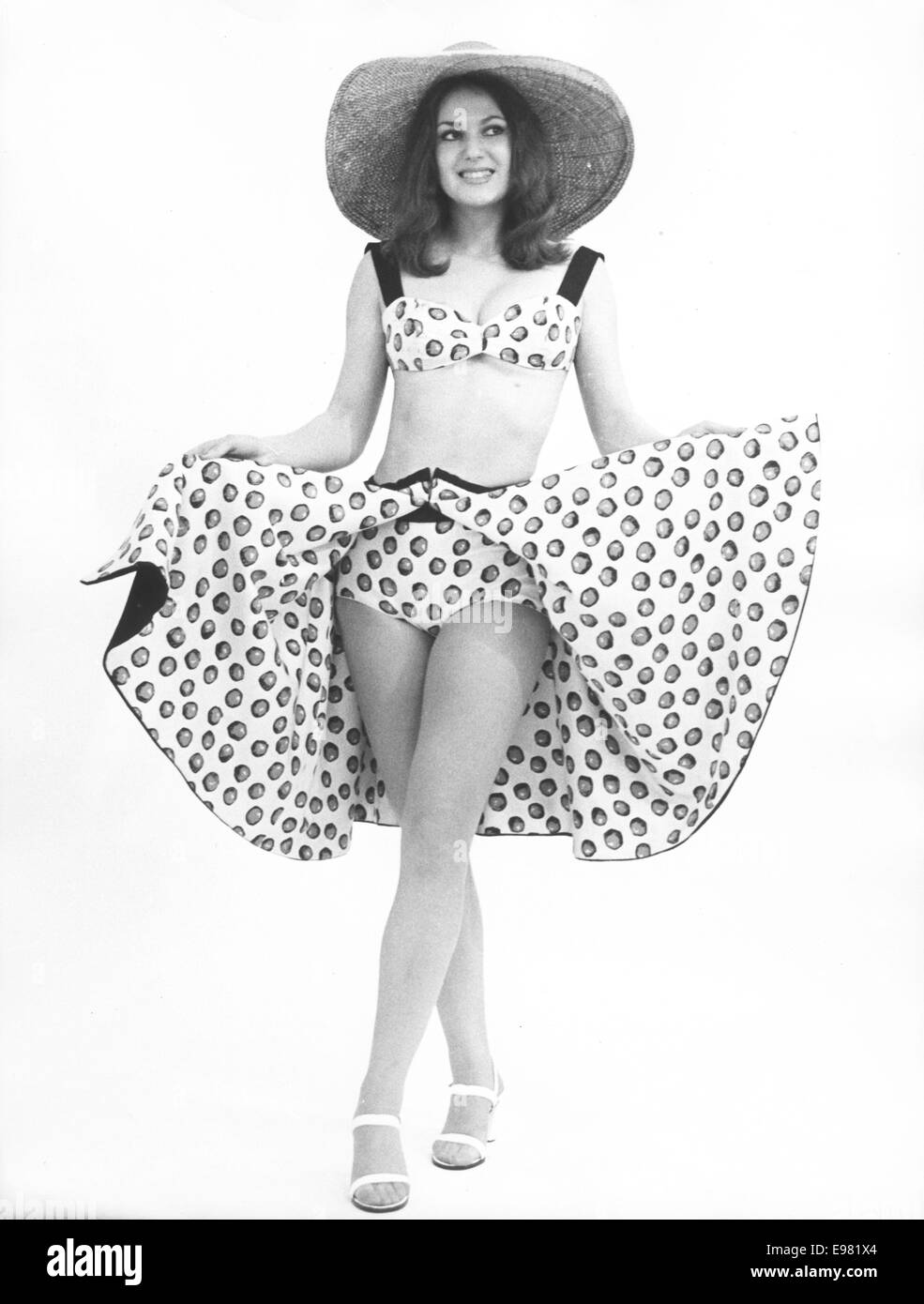 London, UK, UK. 25 Jan, 1975. Miss France 1973 ISABELLE KRUMACKER, un jeune homme de 18 ans Baker, porte Rimini pour l'été. Isabelle étend sa jupe pour montrer ce quartier à la mode ensemble de plage en toile noir sur blanc réversible à pois noir et chemise de bikini et couvrir jusqu'créé par Royal Street couturier Novak. © Keystone Photos/ZUMA/ZUMAPRESS.com/Alamy fil Live News Banque D'Images