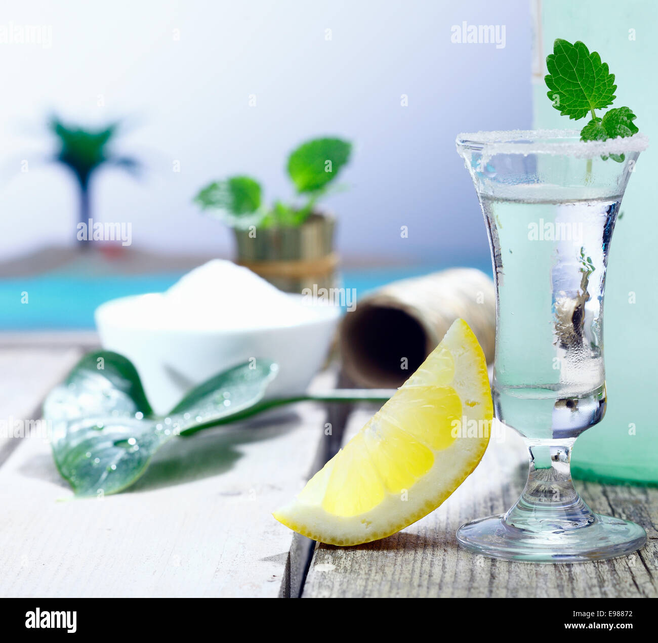 Garni d'une vodka givré verre avec une tranche de citron acidulé frais chaser servi sur une terrasse en bois le long de la mer, dans un Banque D'Images