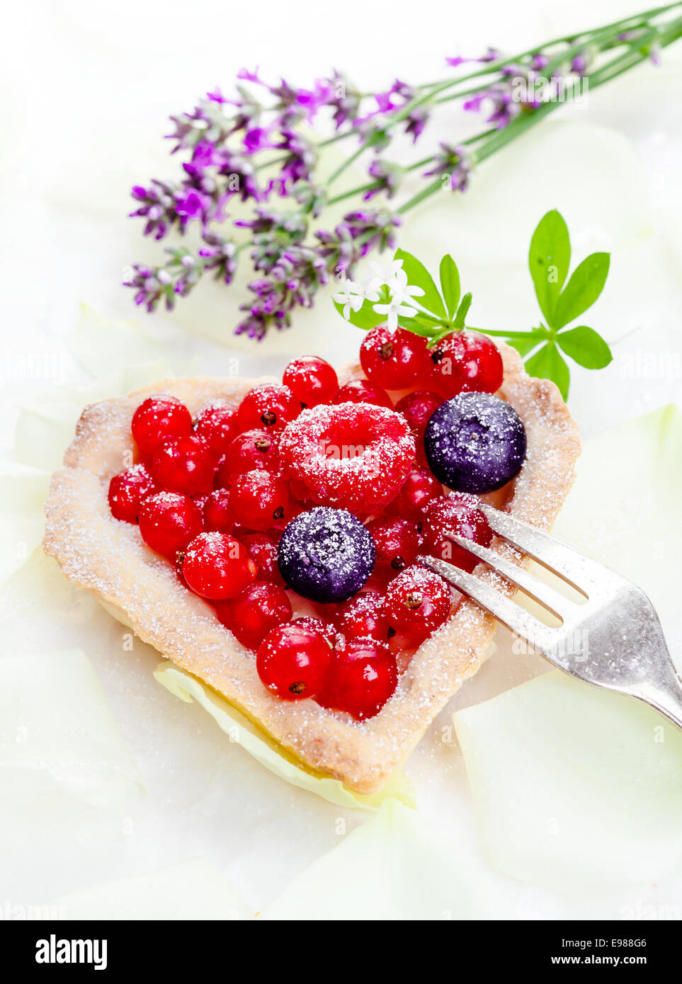 Tartelette groseille en forme de cœur avec des fruits frais entiers givré avec du sucre et servi avec un gâteau d'argent fork Banque D'Images