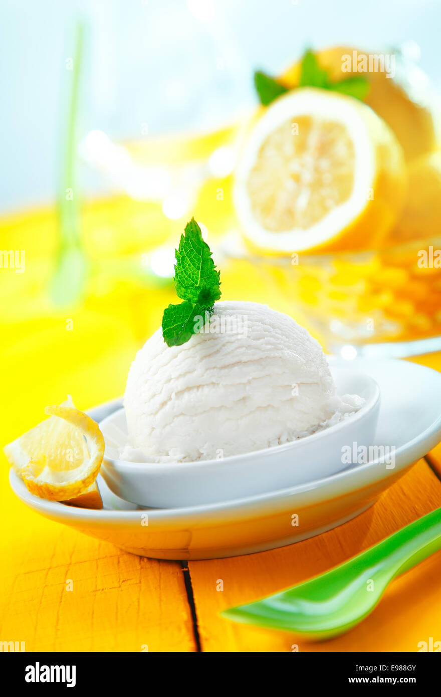 Servant de sorbet au citron aigre rafraîchissant icecream avec feuilles de menthe servi sur une table jaune inclinée Banque D'Images