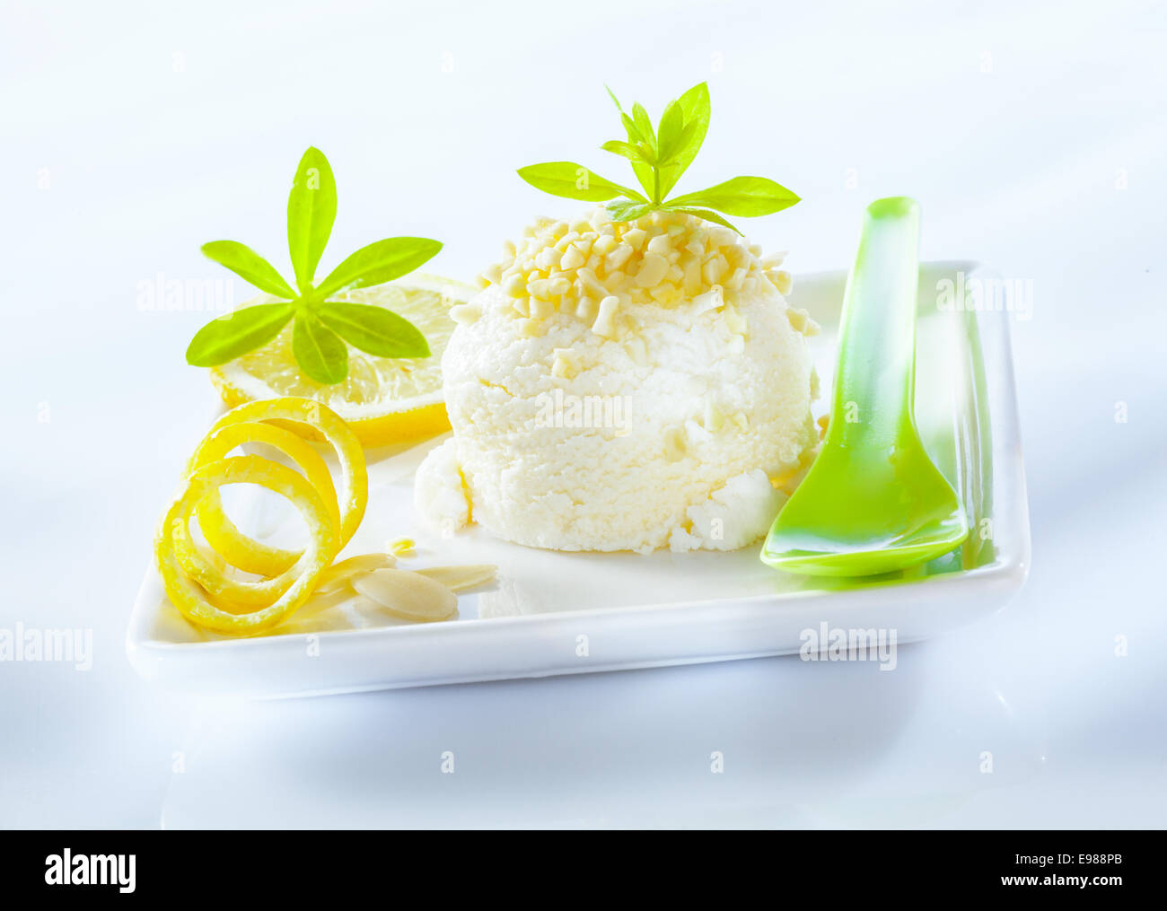 Sorbet au citron aigre rafraîchissante dessert servi avec le zeste de citron en spirale sur une assiette en porcelaine carrée Banque D'Images