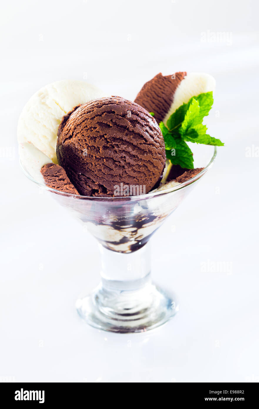 Verre à cocktail en verre rempli de billes de chocolat crémeux texturé et crème glacée à la vanille garnie de mint Banque D'Images