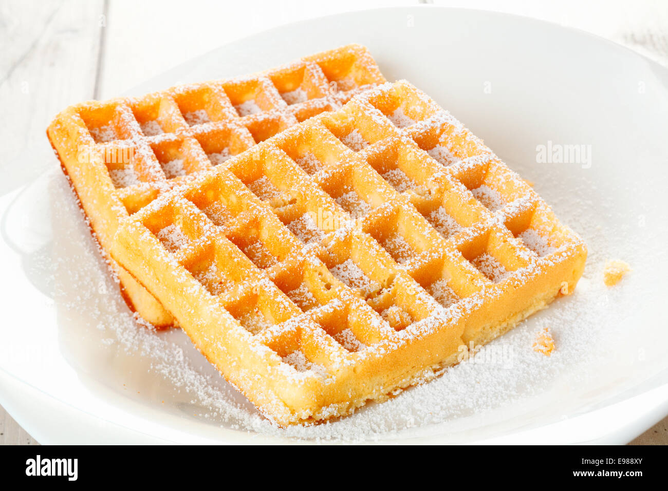 Une paire de délicieuses gaufres fraîches, saupoudrées de sucre un placé dans un bol peu profond chine blanc Banque D'Images