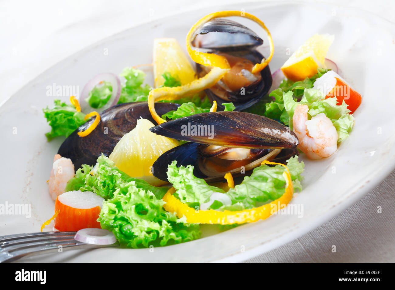 Servant de délicieux fruits de mer salade avec les moules, les crabes et les crevettes sur un lit de salade verte croquante garnie avec orange peel Banque D'Images