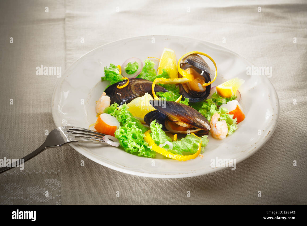 Servir sur une assiette de salade de fruits de mer frais et des moules avec des légumes verts, du crabe et des crevettes garnie avec orange peel Banque D'Images