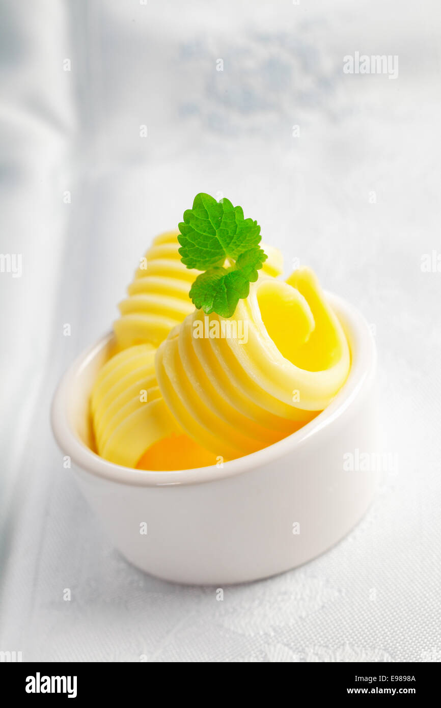 Crème fraîche beurre roulée de chauffage dans un petit individu chine ramikin pour servir au cours d'une table ou d'un événement Banque D'Images