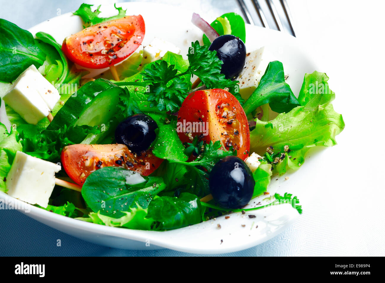 Servant de délicieux salade grecque à la feta, olives, d'herbes, de tomate et de laitue dans un plat individuel comme accompagnement d'un repas Banque D'Images