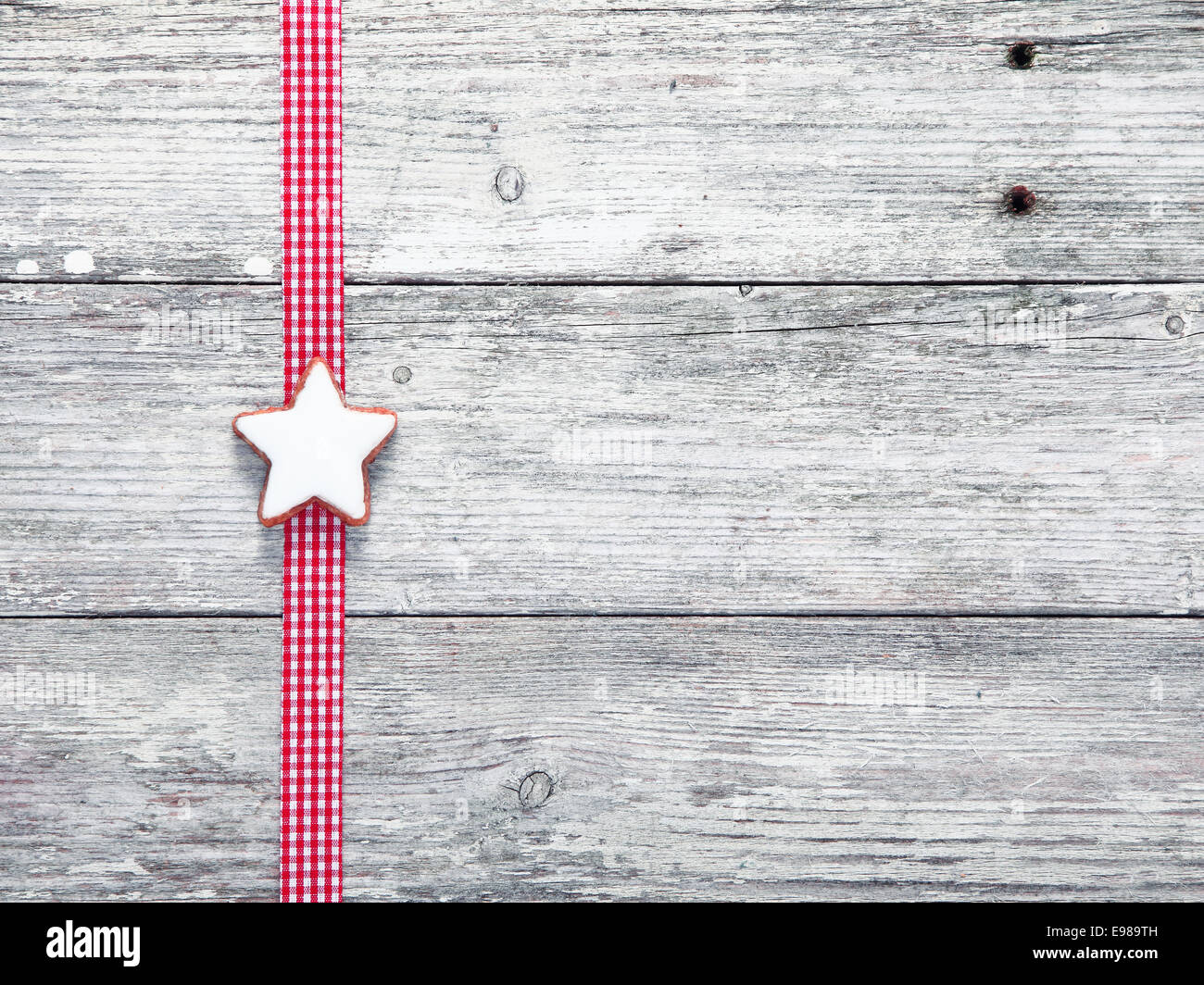 L'étoile de Noël biscuit et ruban de fête sur planches de bois patiné blanc grungy avec texture en similibois et copyspace Banque D'Images