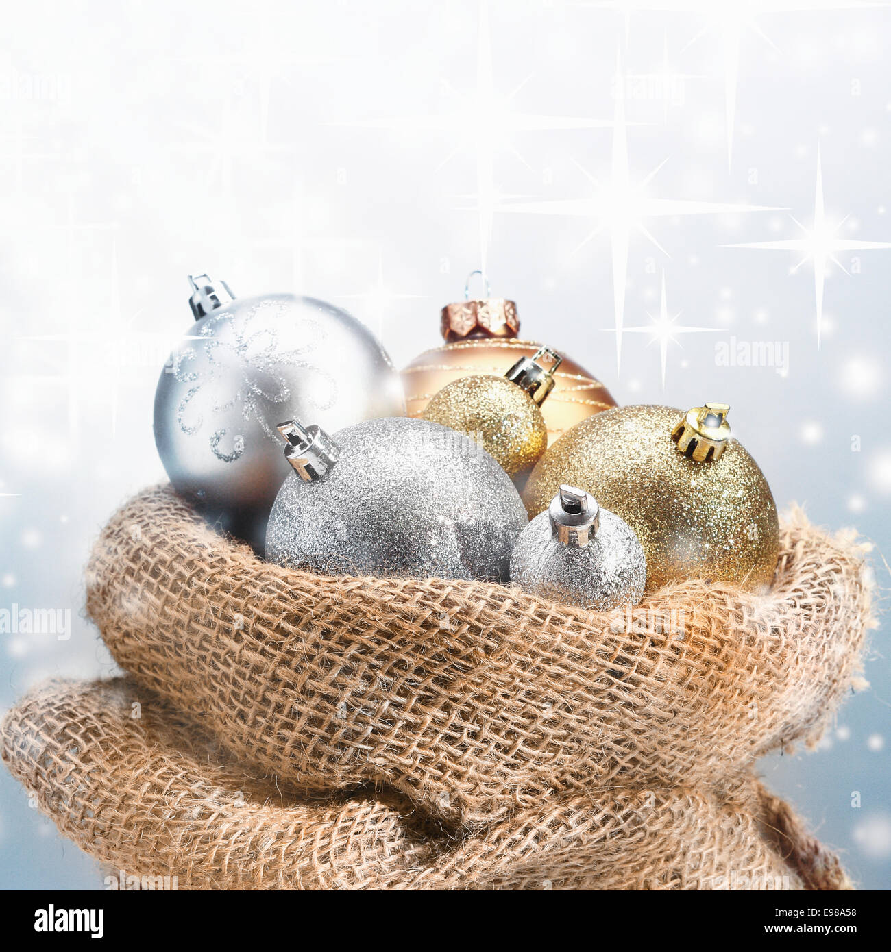 Sac en toile de jute rustique plein de décorations de Noël avec des boules d'or et d'argent, sous la neige étincelante avec copyspace Banque D'Images