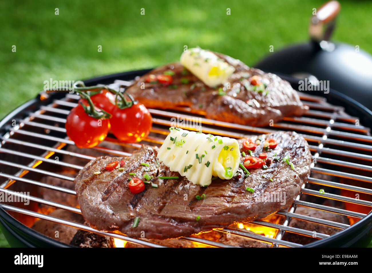 Partie de succulent steak maigre surmonté avec le beurre et les herbes grillées sur une grille sur des charbons ardents dans un barbecue Banque D'Images