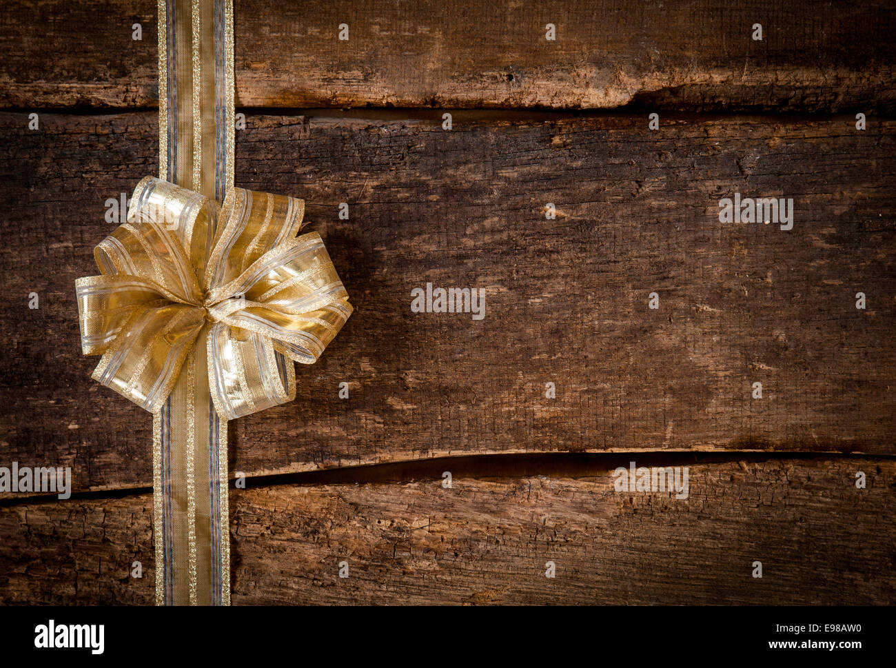 Ruban d'or de fête et bow border à gauche du châssis sur un dark grunge textured background rustique en bois avec copyspace pour votre Noël, anniversaire ou souhaits d'anniversaire ou d'invitation Banque D'Images