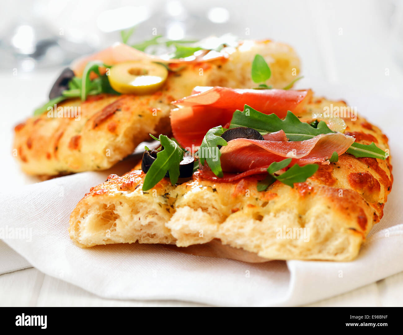 Délicieux du pain focaccia italienne traditionnelle avec du jambon, des olives et de la fusée sur une serviette blanche, vue en gros Banque D'Images