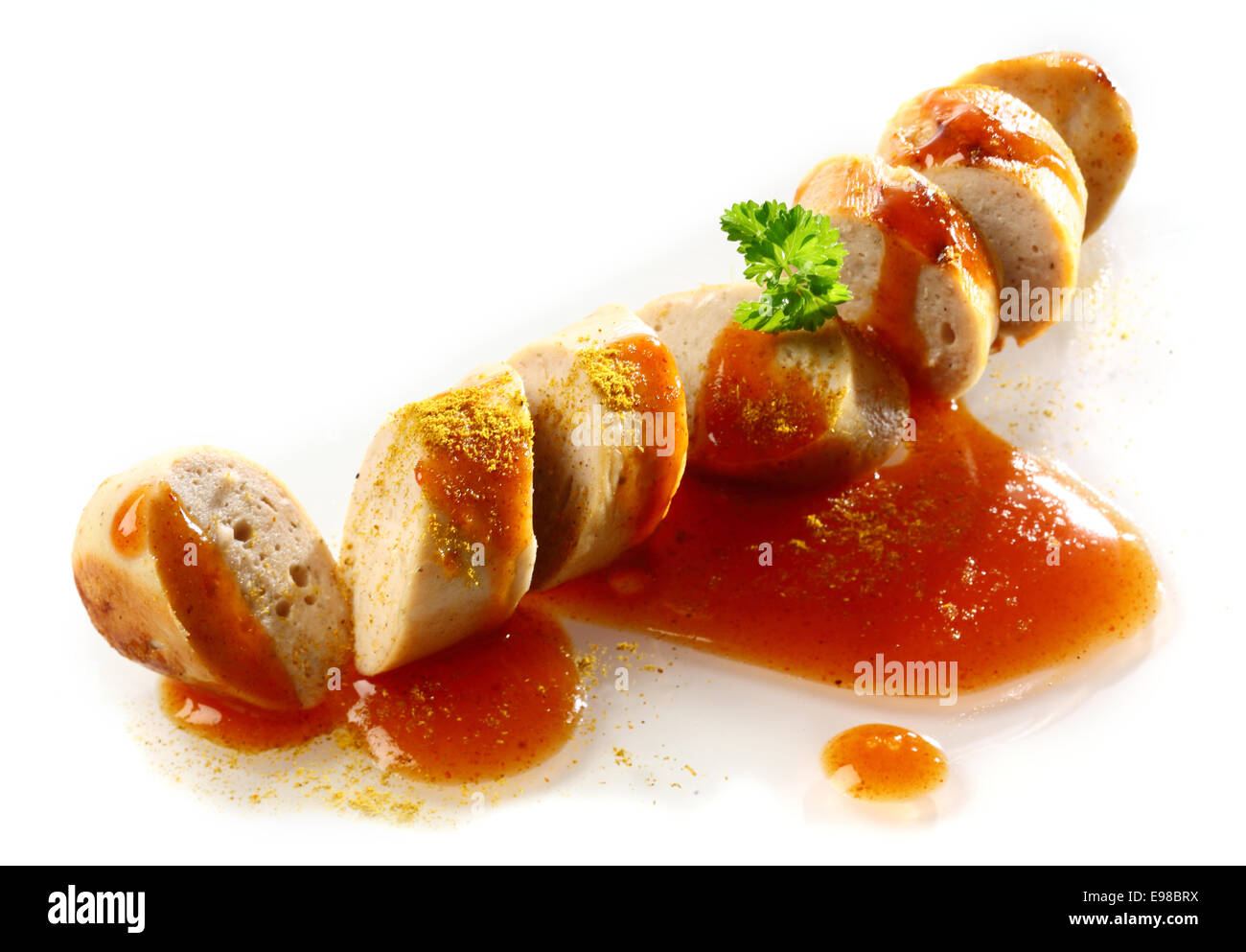 Saucisse épicée fumé grillé en tranches et servi en partie grâce à la tomate ketchup garnie de persil over white Banque D'Images