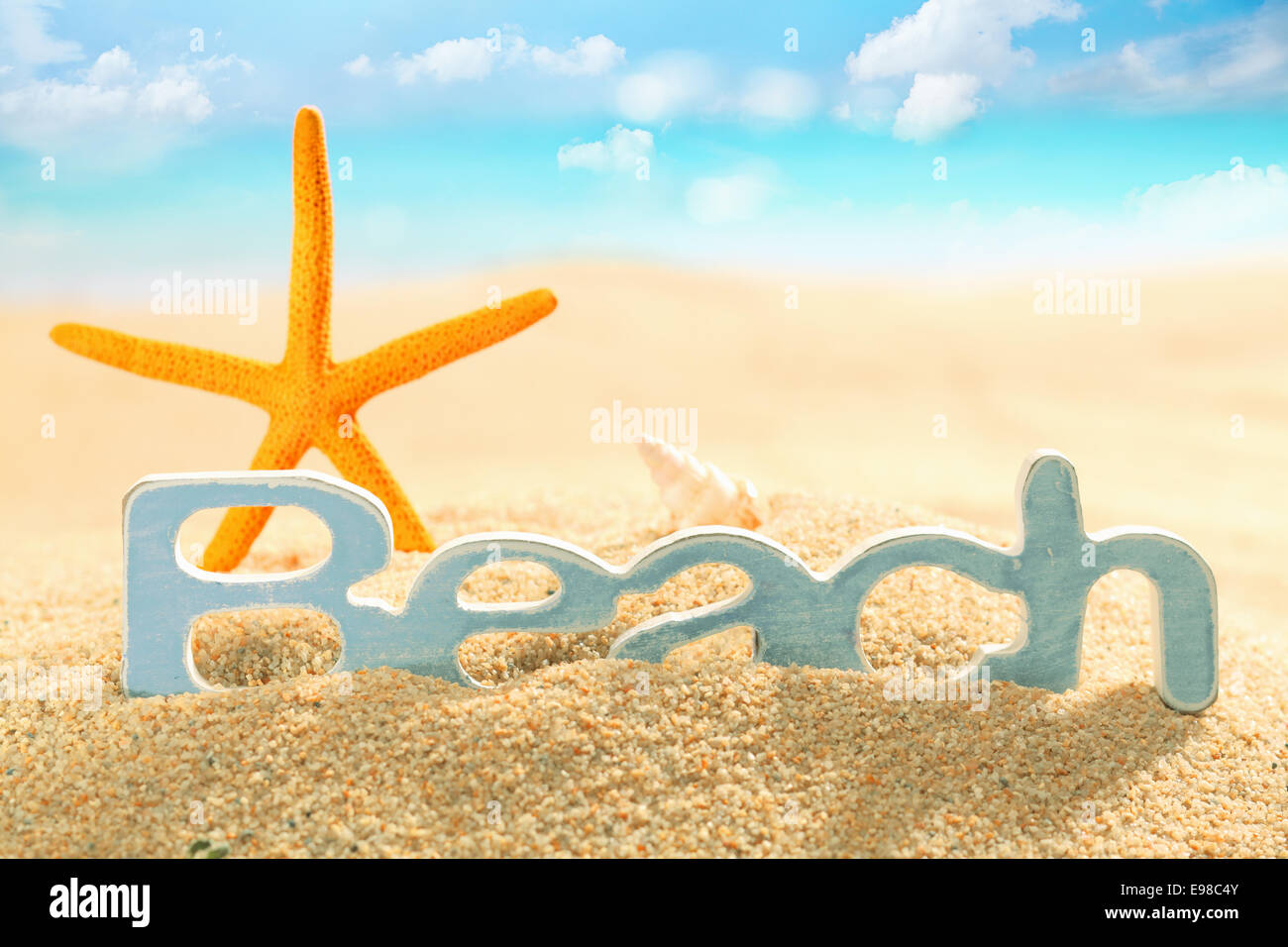 Étoile de mer orange coloré debout derrière un panneau pour plage de golden sea sable sur le bord de la mer d'une plage tropicale idyllique sur une chaude journée d'été Banque D'Images