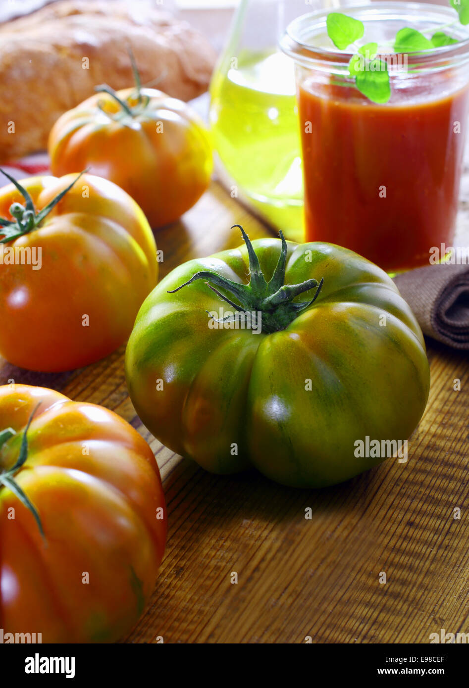 Vert Vert tomate côtelée sur une table de cuisine avec d'autres tomates rouges mûres pour une utilisation dans la préparation de la pâte de tomate fraîche comme ingrédient dans la cuisine italienne Banque D'Images
