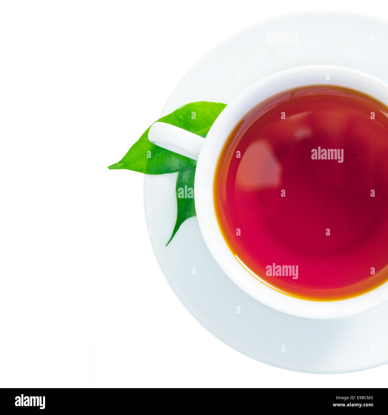 Vue de dessus d'une jolie tasse de thé fraîchement infusé avec deux feuilles de thé vert dans la soucoupe isolated on white Banque D'Images