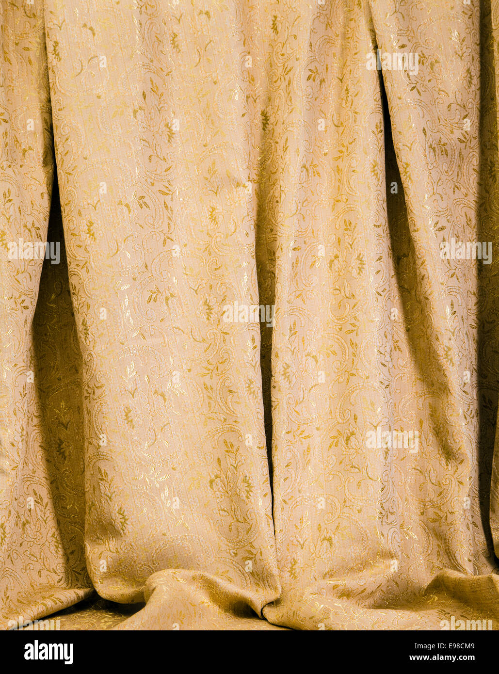 Rideaux suspendus de l'or avec un motif damassé luxueux de feuilles d'acanthe brillant pour un élégant décor intérieur Banque D'Images