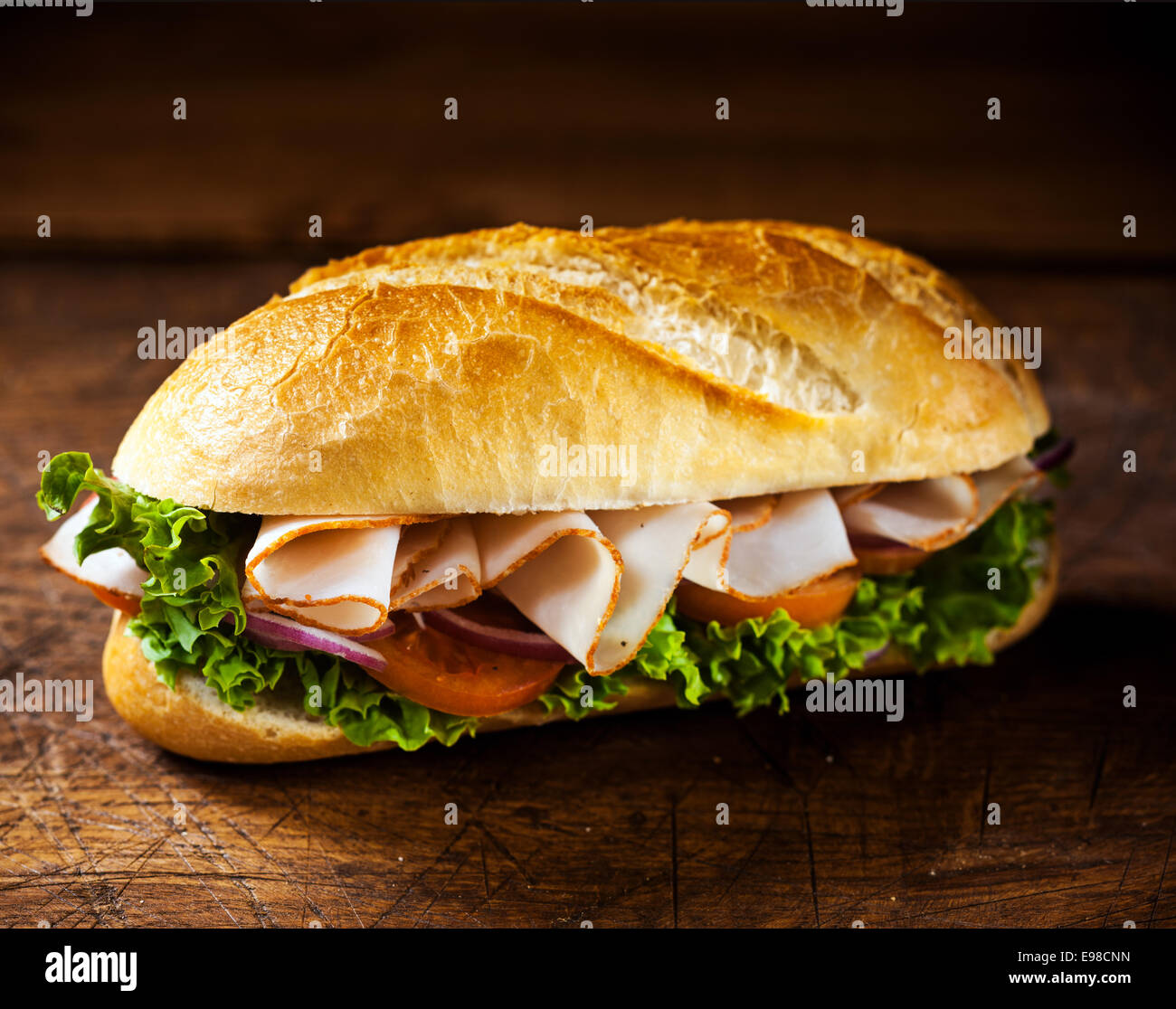 Rouleau d'or croûté frais avec des tranches de jambon et les ingrédients de la salade de laitue, tomate et y compris l'oignon prêt préparé pour une délicieuse collation sur une table en bois avec copyspace Banque D'Images