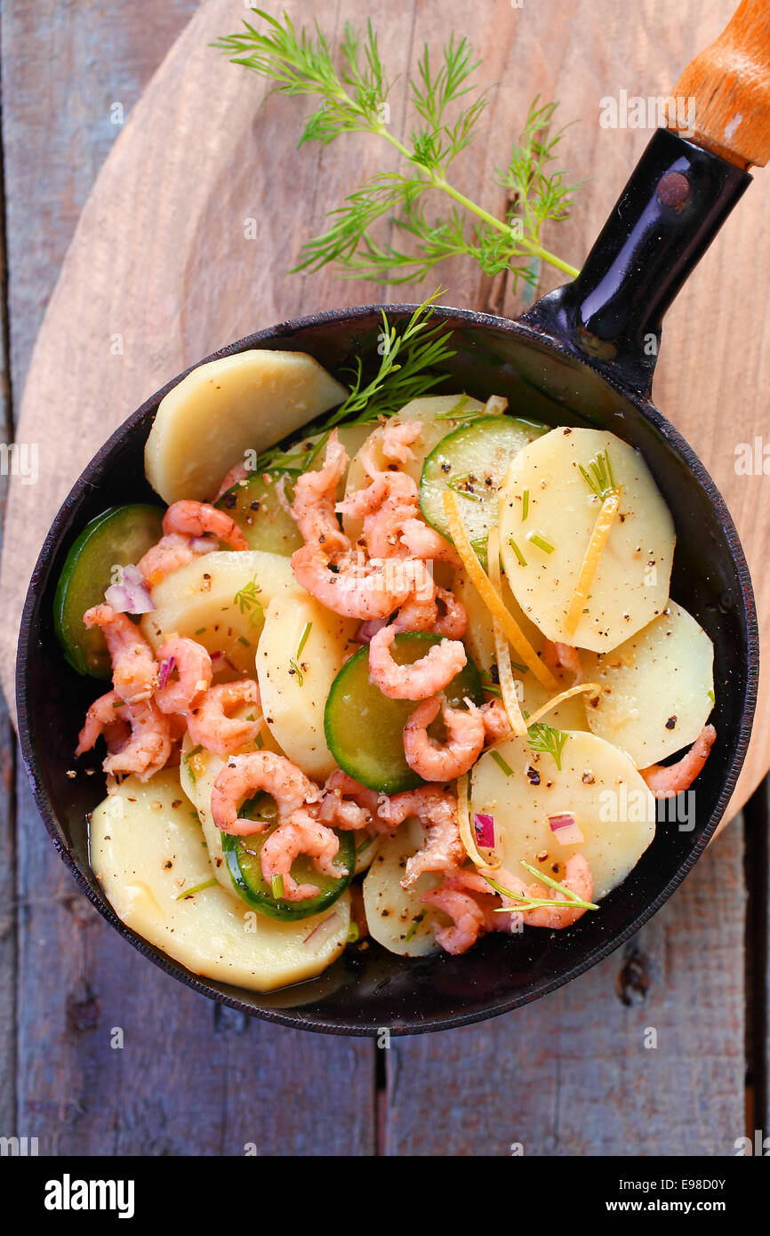 De délicieux repas gastronomique de langoustines poêlé aux pommes de terre et la courgette garnie d'herbes et servi dans une poêle en métal Banque D'Images