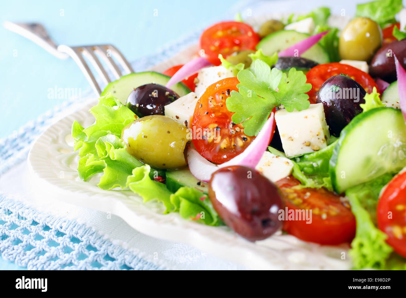 Delicious fresh mixed salade grecque avec croustillant de laitue, tomate cerise, concombres, oignons, olives et fromage feta servi sur fond blanc Banque D'Images
