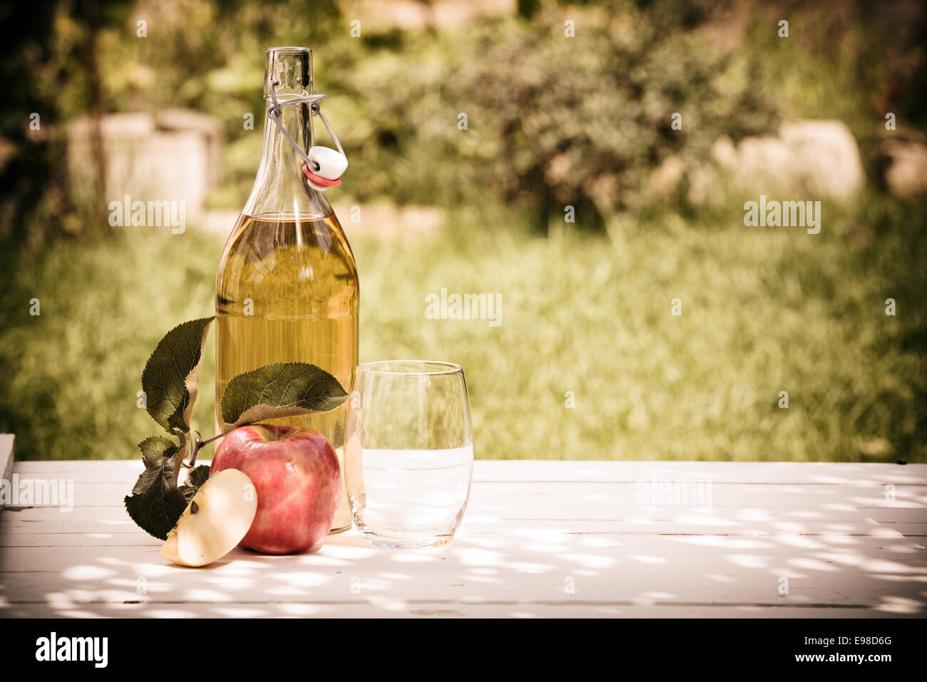 Bouteille de jus de pomme rafraîchissante à partir de pommes fraîches récoltées dans le jardin extérieur permanent sur une table en bois rustique Banque D'Images