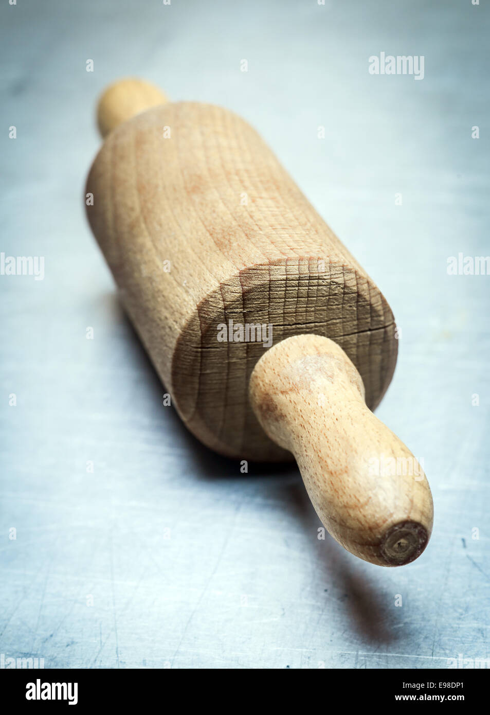 Vue rapprochée de la poignée d'un rouleau à pâtisserie en bois debout à un angle oblique sur un fond dans les tons bleus avec vignettage Banque D'Images