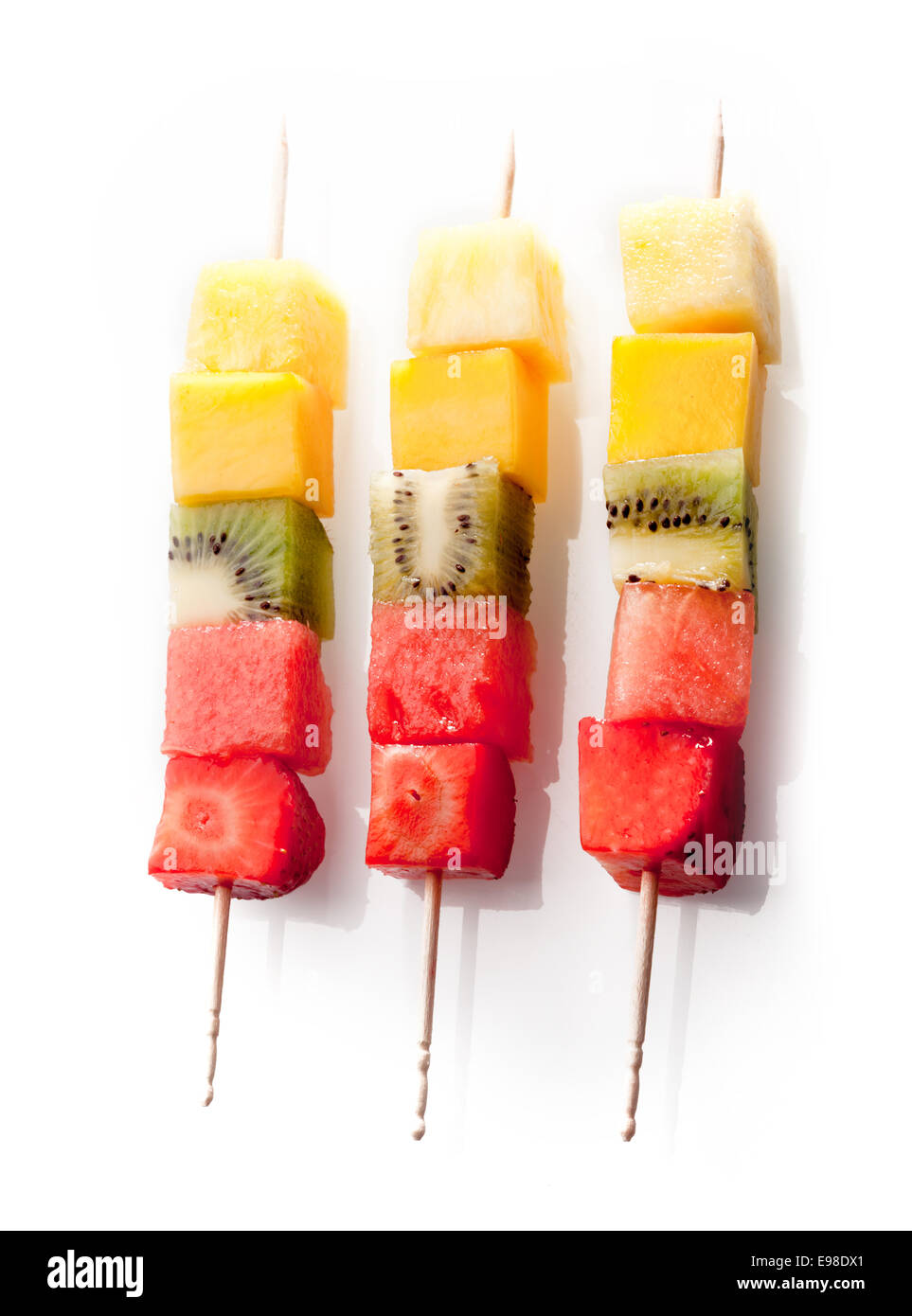 Trio de fruits frais colorés, brochettes de fruits avec coupé nettement les cubes de fruits tropicaux et exotiques disposés en une rangée sur un fond blanc Banque D'Images