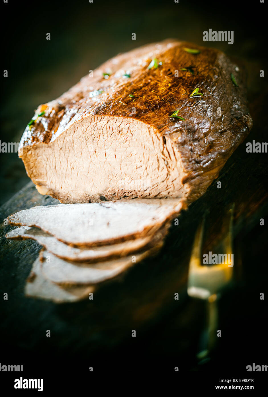 Tranches de pain de viande allemande cuit dans une cocotte et garnir de fines herbes fraîches hachées sur un fond sombre avec une fourchette à découper Banque D'Images