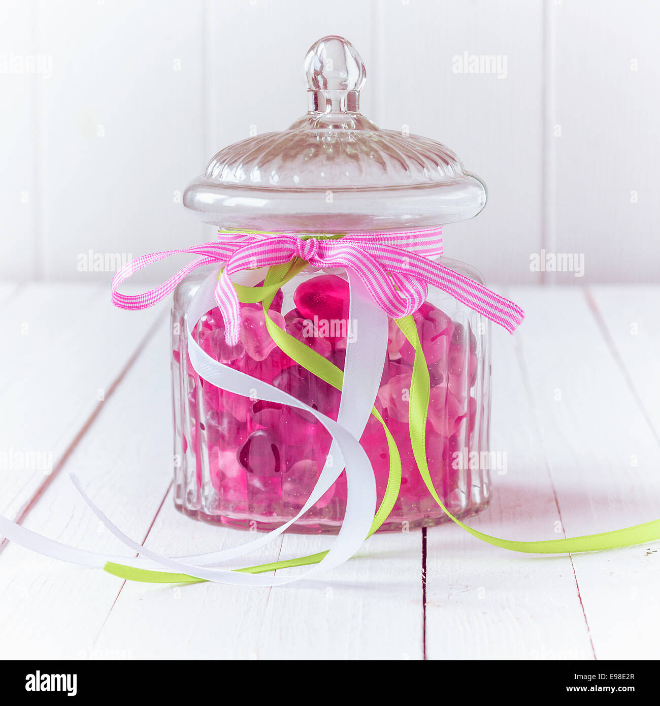 Verre ancien pot rempli de bonbons bonbons gomme rose et attaché avec trois rubans avec le blanc, vert et rose couleurs avec un Banque D'Images