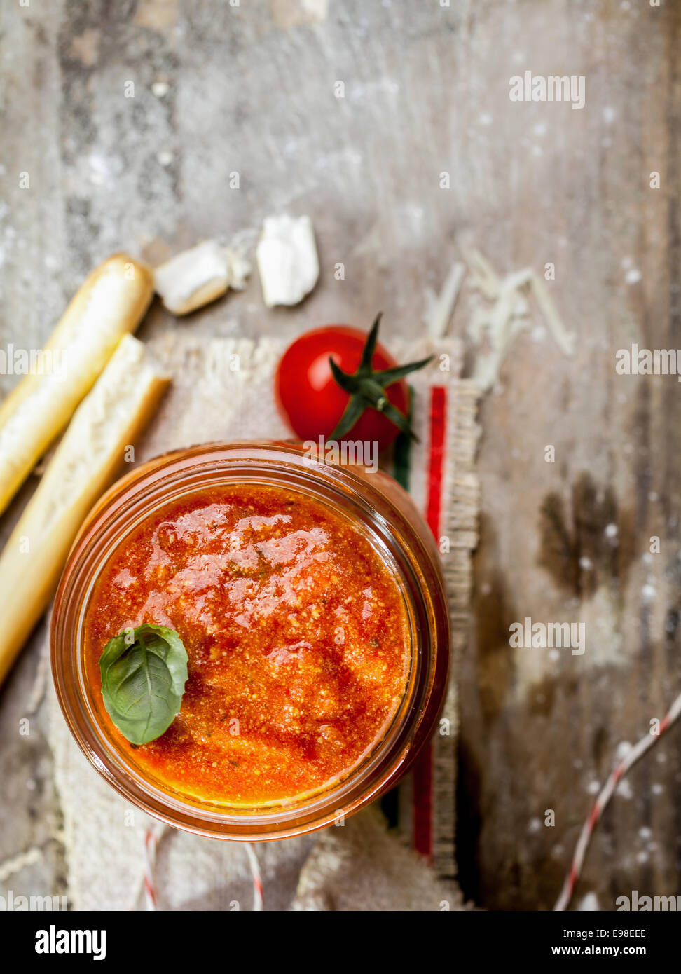 Vue de dessus d'un bocal en verre de hot spicy tomato relish avec grassini ou bâtonnets de pain italien sur un fond de bois rustique grungy avec copyspace Banque D'Images