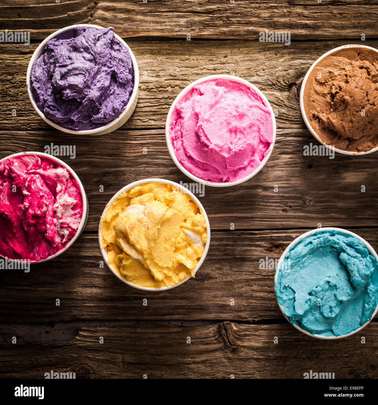 Crémeux savoureuses glaces italiennes colorés dans des bains à remous pour une fête ou occasion festive servi sur une vieille table en bois rustique, overhead view Banque D'Images