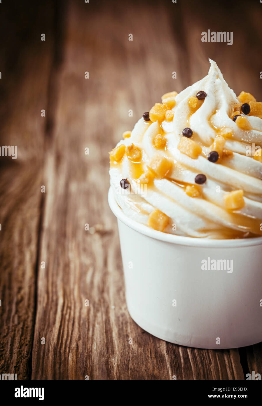 Twirl sain de parfait au yogourt faible en gras surmontées de Nutrifer servi dans un bain à remous à emporter en plastique blanc sur un vieux comptoir en bois rustique avec copyspace Banque D'Images