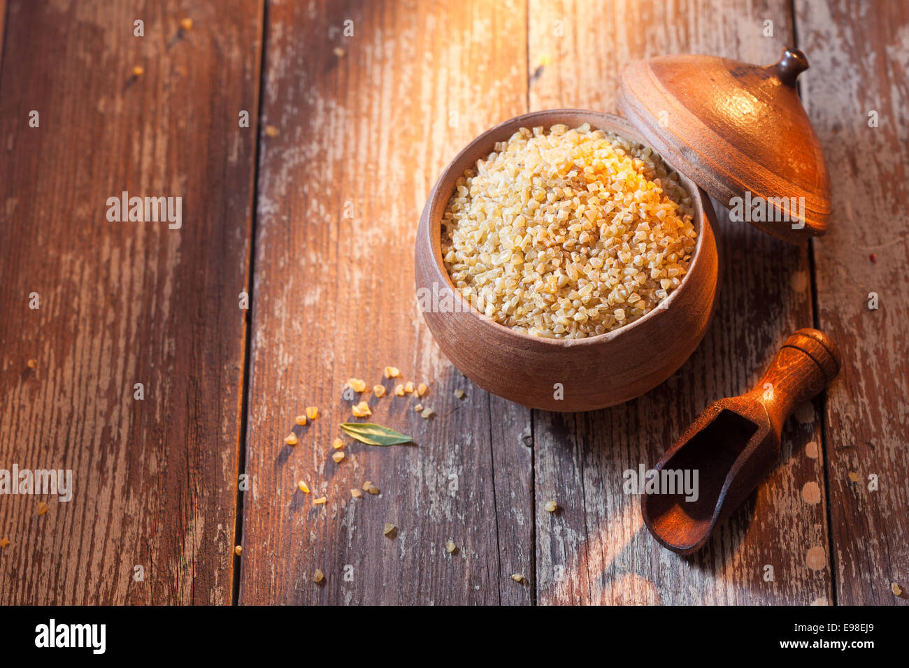 Boulgour ou blé concassé dans un pot en terre cuite utilisé dans la cuisine du Moyen-Orient, high angle view sur de vieux bois texturé avec copyspace Banque D'Images