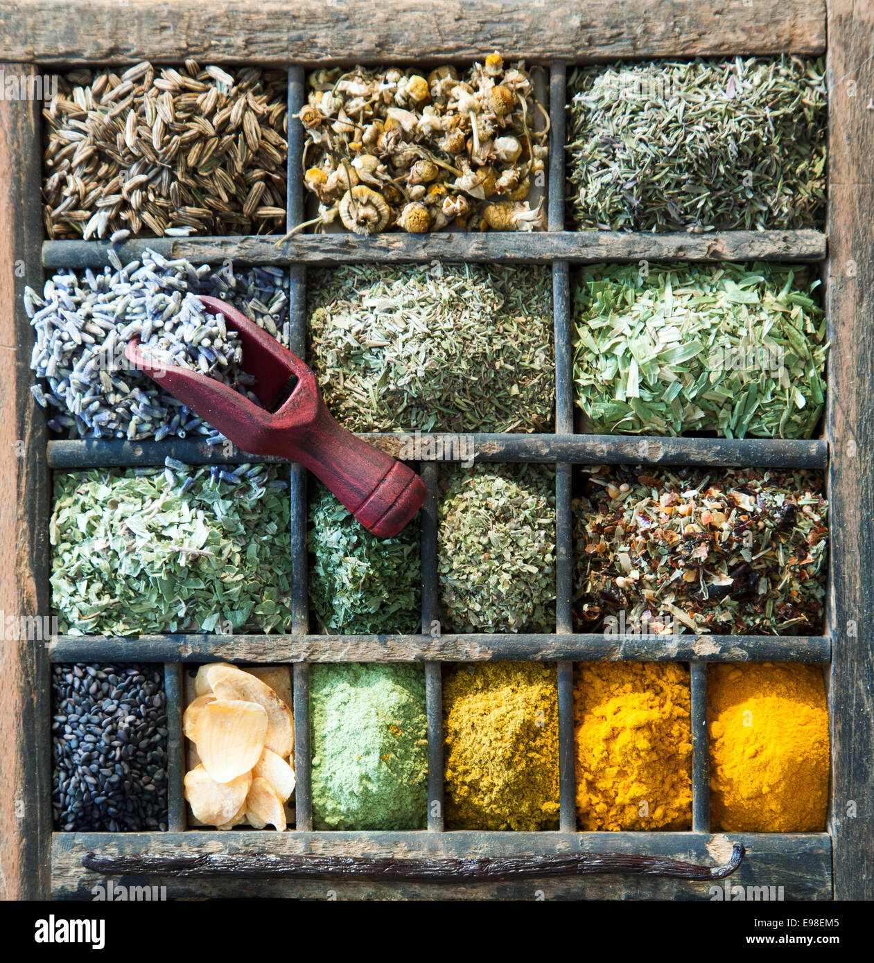 Les herbes et épices assorties dans un vieux bac imprimantes en bois avec une petite cuiller en bois, overhead view Banque D'Images