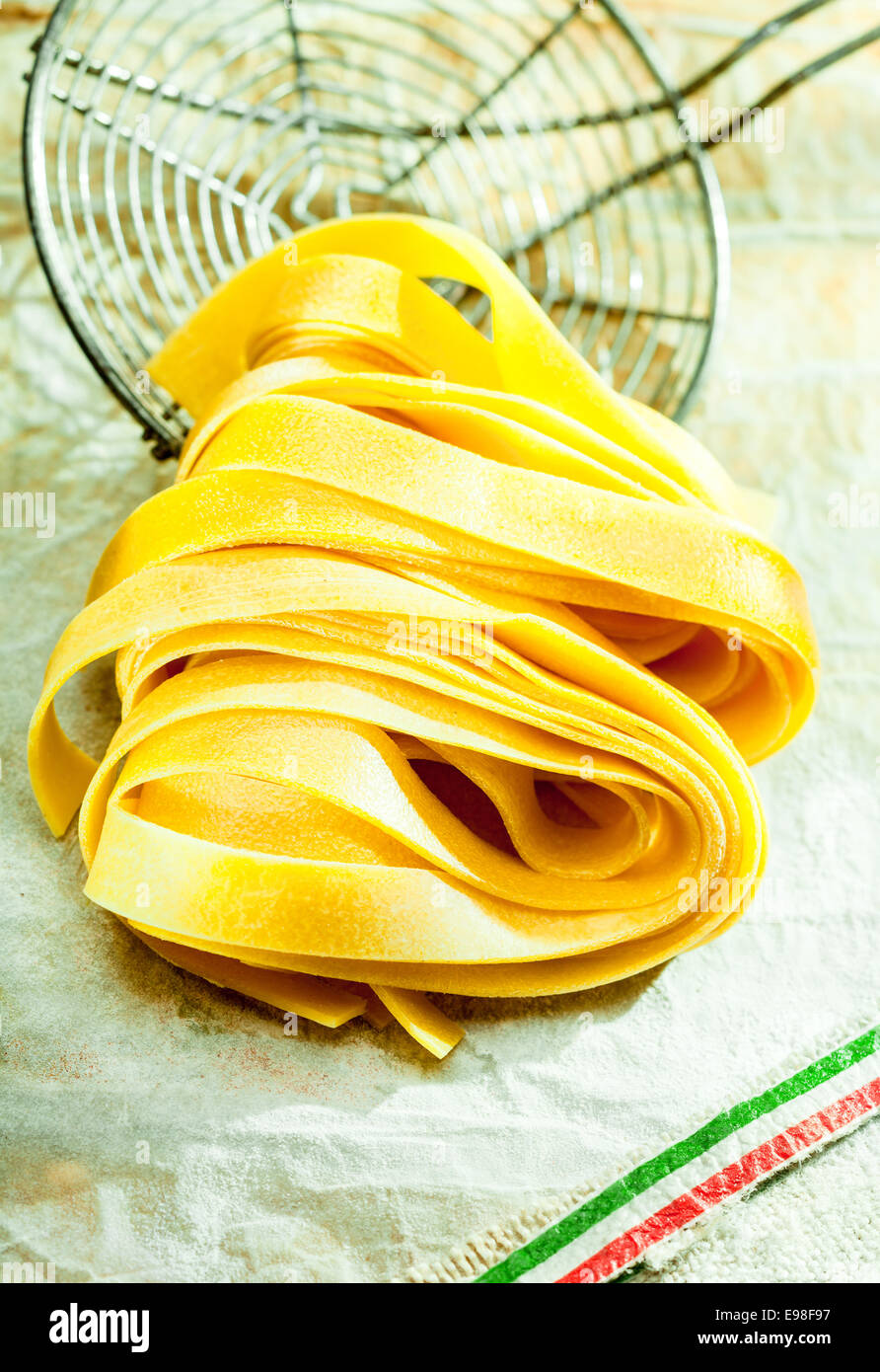 Fettuccine cuits pâtes italiennes allongé sur une vieille passoire cuisine fil durant la préparation et la cuisson d'un repas méditerranéen traditioal Banque D'Images